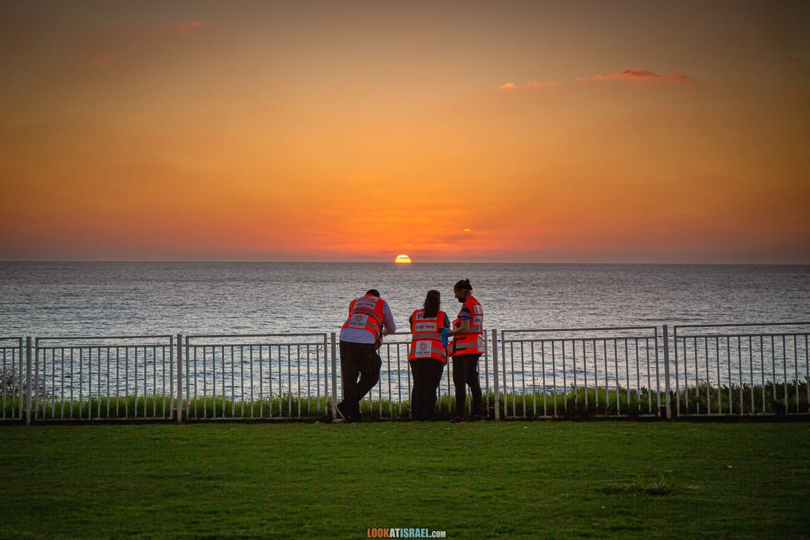 Три парамедика смотрят на закат у моря